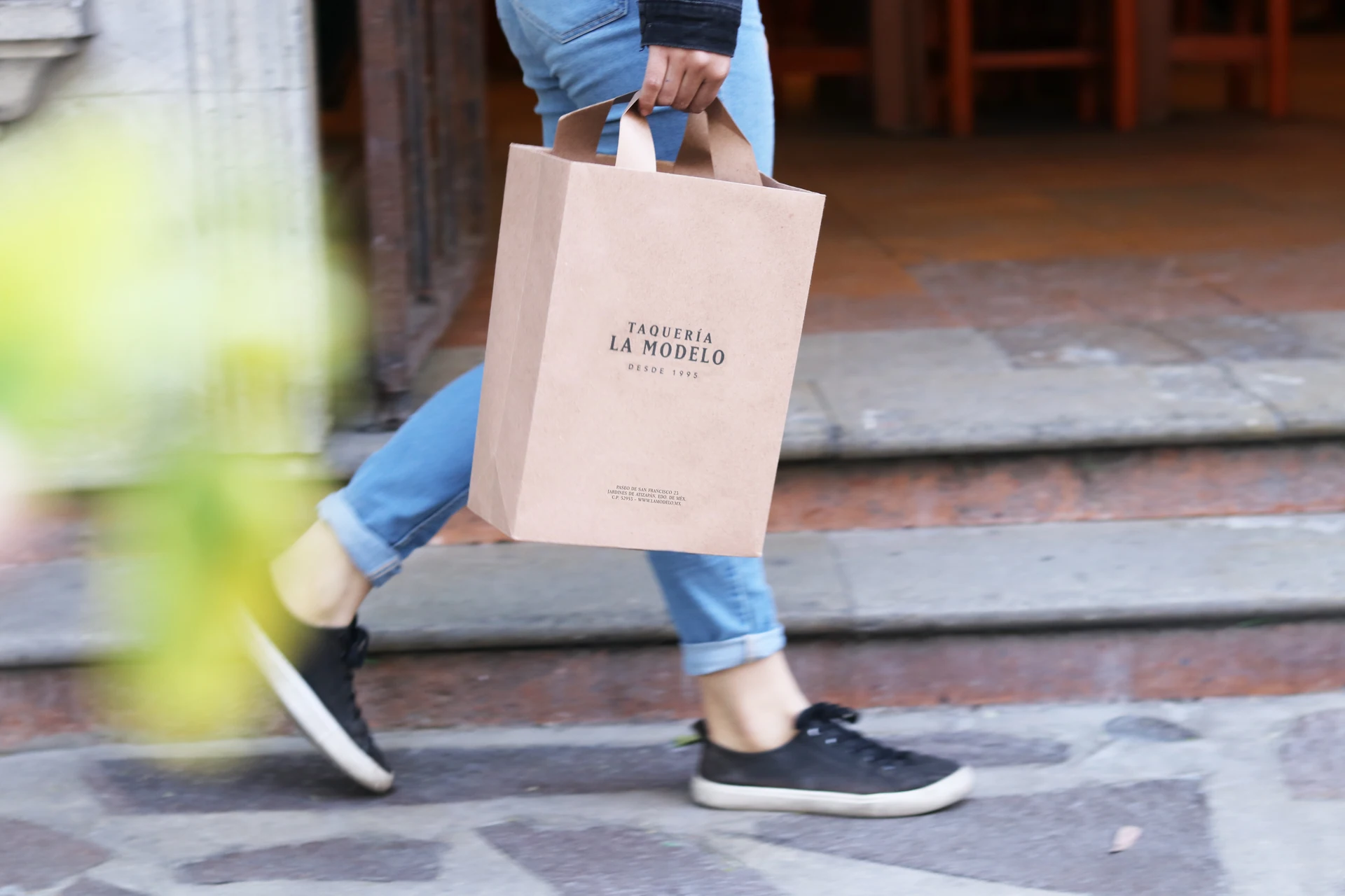 Persona con bolsa de Taquería La Modelo caminando por la calle