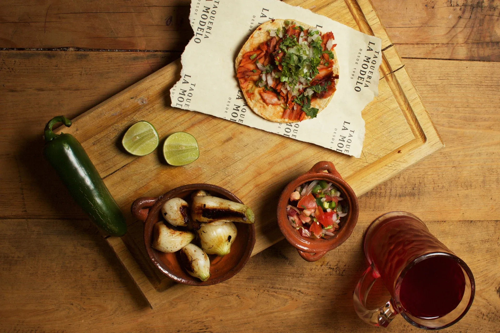 Tacos, salsa y limones servidos sobre papel de marca de Taquería La Modelo